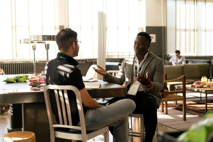 Two men engage in a conversation in a relaxed setting.